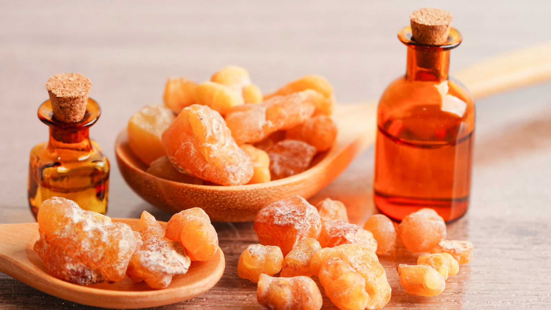 Two jars of frankincense essential oil on a table next to a bowl of crystals.