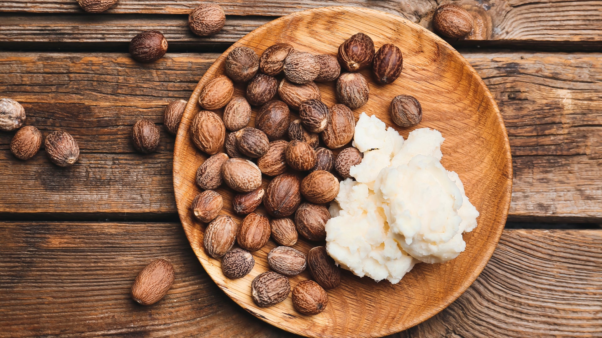 A plate full of shea tree nuts and a lump of shea butter.